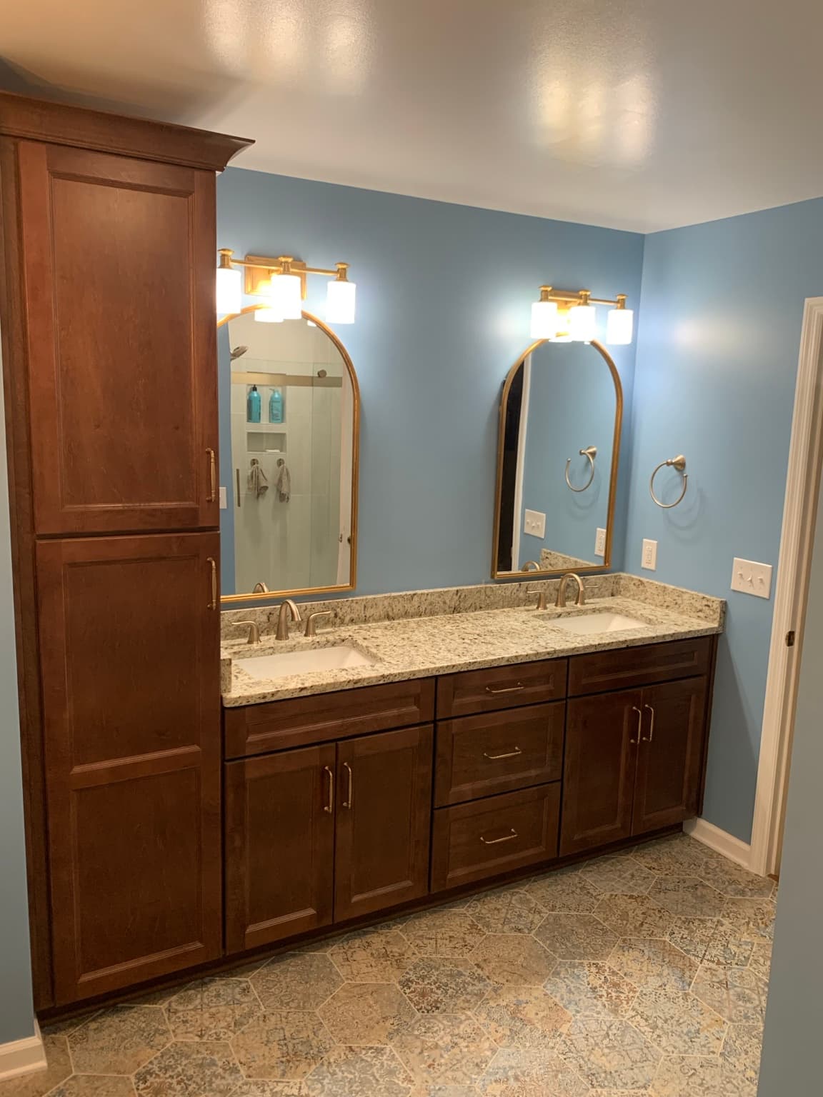 Completed bathroom with installed mirrors, light fixtures, bathroom hardware, and cabinet pulls